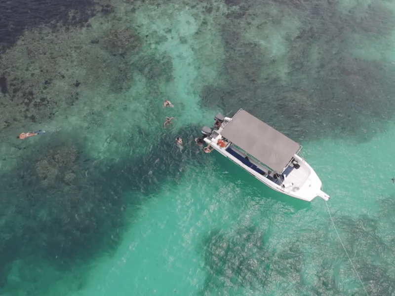 A boat cruising through the turquoise waters of Sainte Anne Marine National Park on a seychelles boat tour from Victoria, Mahé
