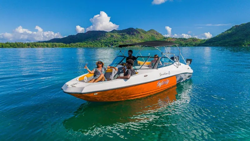 A small wooden boat anchored off St Pierre Island with snorkelers entering crystal-clear water on a seychelles boat tour from Praslin