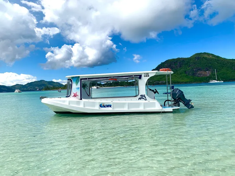 Passengers aboard a glass-bottom boat viewing the coral reef below the surface at Sainte Anne Marine National Park on a seychelles boat tour from Eden Island Marina
